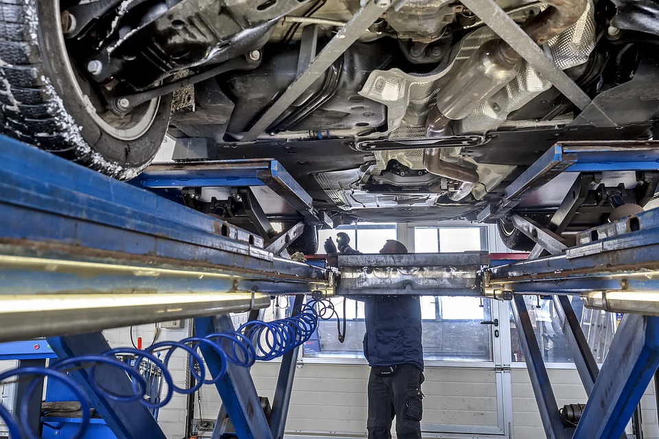 Garagiste qui réalise le contrôle technique d'une voiture en vérifiant ses pneus