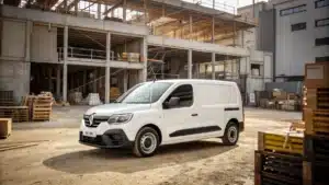Un Renault Express Van blanc garé devant une zone de chantier ou un entrepôt, accompagné d’outils professionnels ou de boîtes de livraison dans le champ visuel.